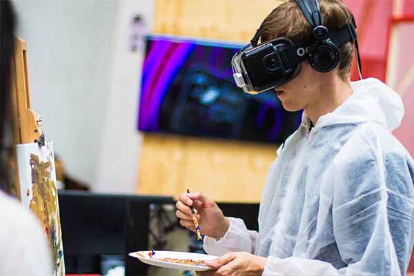 A young person painting with VR-glasses on